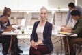 Portrait of smiling businesswoman sitting on chair with team working in background Royalty Free Stock Photo