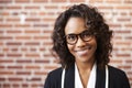 Portrait Of Smiling Businesswoman Wearing Glasses Standing Against Brick Wall In Modern Office Royalty Free Stock Photo