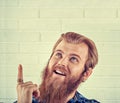 Portrait of a smiling casual blue shirt man pointing finger up isolated on a white brick wall background. Yellow Toned image, Royalty Free Stock Photo