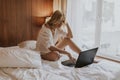 Smiling casual young woman using laptop in bed at home Royalty Free Stock Photo