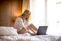 Smiling casual young woman using laptop in bed at home Royalty Free Stock Photo