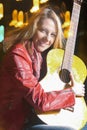 Portrait of Smiling Caucasian Blond Woman Playing The Guitar Outdoors at Night. Royalty Free Stock Photo