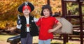 Portrait of smiling caucasian boys in pirate and aviator costumes standing at park Royalty Free Stock Photo