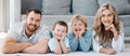 Portrait of smiling caucasian family of four lying and relaxing on the floor at home. Carefree loving parents bonding Royalty Free Stock Photo