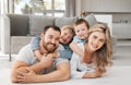 Portrait of smiling caucasian family of four relaxing on floor in lounge at home. Playful sons lying and clinging on Royalty Free Stock Photo