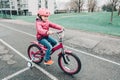 smiling Caucasian preschooler girl riding pink bike bicycle in helmet on backyard road outside on spring autumn day Royalty Free Stock Photo