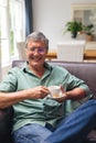 Portrait of smiling caucasian senior man having coffee while sitting on sofa at home Royalty Free Stock Photo