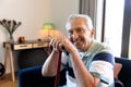 Portrait of smiling caucasian senior man with walking cane sitting on chair in living room at home Royalty Free Stock Photo