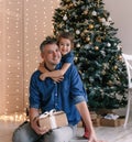 Portrait of a smiling charming girl hugging her father from behind near a festive Christmas tree, the family celebrates Royalty Free Stock Photo