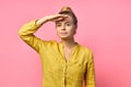 Portrait of a smiling cheerful girl in summer clothes looking far away with hand at her forehead isolated over pink Royalty Free Stock Photo