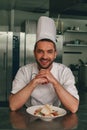 Portrait of smiling chef in uniform with cesar salat on modern kitchen of restaurant Royalty Free Stock Photo