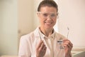 Portrait of smiling confident dentist wearing surgical mask and eyewear while holding dental equipments