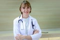 Portrait of smiling confident female doctor in white workwear with stethoscope, standing with arms crossed in clinic hospital. Royalty Free Stock Photo