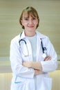 Portrait of smiling confident female doctor in white workwear with stethoscope, standing with arms crossed in clinic hospital. Royalty Free Stock Photo