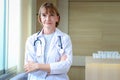 Portrait of smiling confident female doctor in white workwear with stethoscope, standing with arms crossed in clinic hospital. Royalty Free Stock Photo