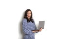 Portrait, smiling confident pretty woman long sleeve dress, holding grey laptop device and typing while standing against solid whi Royalty Free Stock Photo