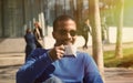 Portrait of smiling confident young African-American businessman in formal wear sitting at bench in city park and Royalty Free Stock Photo