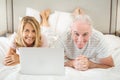 Portrait of smiling couple lying on bed and using laptop Royalty Free Stock Photo