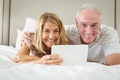 Portrait of smiling couple lying on bed and using laptop Royalty Free Stock Photo