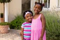 Portrait of smiling cute african american sisters standing with arms around at front yard Royalty Free Stock Photo