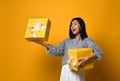 Portrait of a smiling pretty girl holding two gift boxes isolated over yellow background Royalty Free Stock Photo