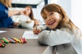 Smiling cute little girl drawing with crayons sitting at table in kitchen at home Royalty Free Stock Photo