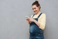 Portrait of a smiling cute pregnant woman using mobile phone Royalty Free Stock Photo