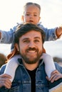 Portrait of a smiling dad with a little serious girl spread her arms out to the sides on his shoulders. Close-up Royalty Free Stock Photo