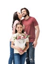 portrait of smiling daughter with bouquet of flowers with parents kissing behind