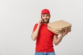 Portrait of a smiling delivery man in red cap talking on mobile phone while holding pizza boxes isolated on the white Royalty Free Stock Photo