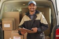 Deliveries are right on schedule. Portrait of a smiling delivery man standing in front of his van holding a package. Royalty Free Stock Photo