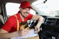 Smiling delivery service worker fill in necessary documents after shipping Royalty Free Stock Photo