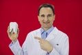 Portrait of a smiling dentist holding a tooth model, isolated on red background Royalty Free Stock Photo