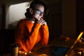 Portrait of smiling designer girl, working at graphic tablet on laptop. Wearing eyeglasses and orange sweater. In dark room home. Royalty Free Stock Photo