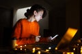 Portrait of smiling designer girl, working at graphic tablet on laptop. Wearing eyeglasses and orange sweater. In dark room home. Royalty Free Stock Photo