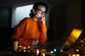 Portrait of smiling designer girl, working at graphic tablet on laptop. Wearing eyeglasses and orange sweater. In dark room home. Royalty Free Stock Photo