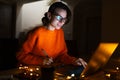 Portrait of smiling designer girl, working at graphic tablet on laptop. Wearing eyeglasses and orange sweater. In dark room home. Royalty Free Stock Photo