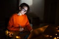 Portrait of smiling designer girl, working at graphic tablet on laptop. Wearing eyeglasses and orange sweater. In dark room home. Royalty Free Stock Photo