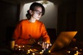 Portrait of smiling designer girl, working at graphic tablet on laptop. Wearing eyeglasses and orange sweater. Royalty Free Stock Photo