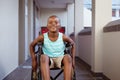 Portrait of smiling disabled african american schoolboy sitting in wheelchair in school corridor Royalty Free Stock Photo