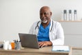 Portrait of smiling doctor looking at camera sitting at desk Royalty Free Stock Photo