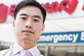 Portrait of smiling doctor outside of the hospital, emergency room sign in the background, Close-Up Royalty Free Stock Photo