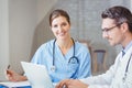 Portrait of smiling doctor sitting at desk with colleague Royalty Free Stock Photo