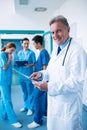 Portrait of smiling doctor standing with x-ray report in corridor Royalty Free Stock Photo