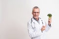 Portrait of smiling doctor with stethoscope holding broccoli isolated.