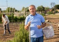 Smiling elderly man amateur gardener standing in home vegetable garden Royalty Free Stock Photo