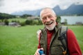 Portrait of smiling elderly man walking outdoors with trekking poles, going on hiking trail. Senior tourists enjoying Royalty Free Stock Photo