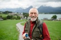 Portrait of smiling elderly man walking outdoors with trekking poles, going on hiking trail. Senior tourists enjoying Royalty Free Stock Photo