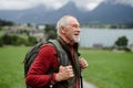 Portrait of smiling elderly man walking outdoors with trekking poles, going on hiking trail. Senior tourists enjoying Royalty Free Stock Photo