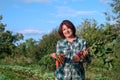 Portrait of a smiling elderly woman with a crop of carrots and lights with tops in her hands in the garden